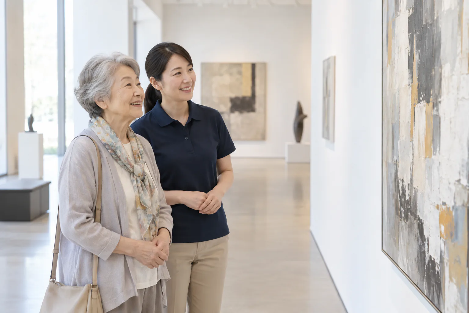 美術館で作品を楽しむ高齢の女性とネイビーのポロシャツのヘルパー